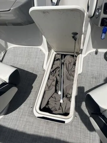 Slide: The Image of 2020 Stingray 208LR boat storage compartment with cover and pole. - 16