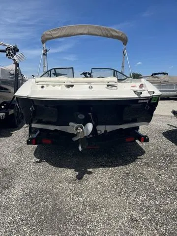 Slide: The Image of 2020 Stingray 208LR boat, rear view, parked on gravel lot under clear blue sky. - 4