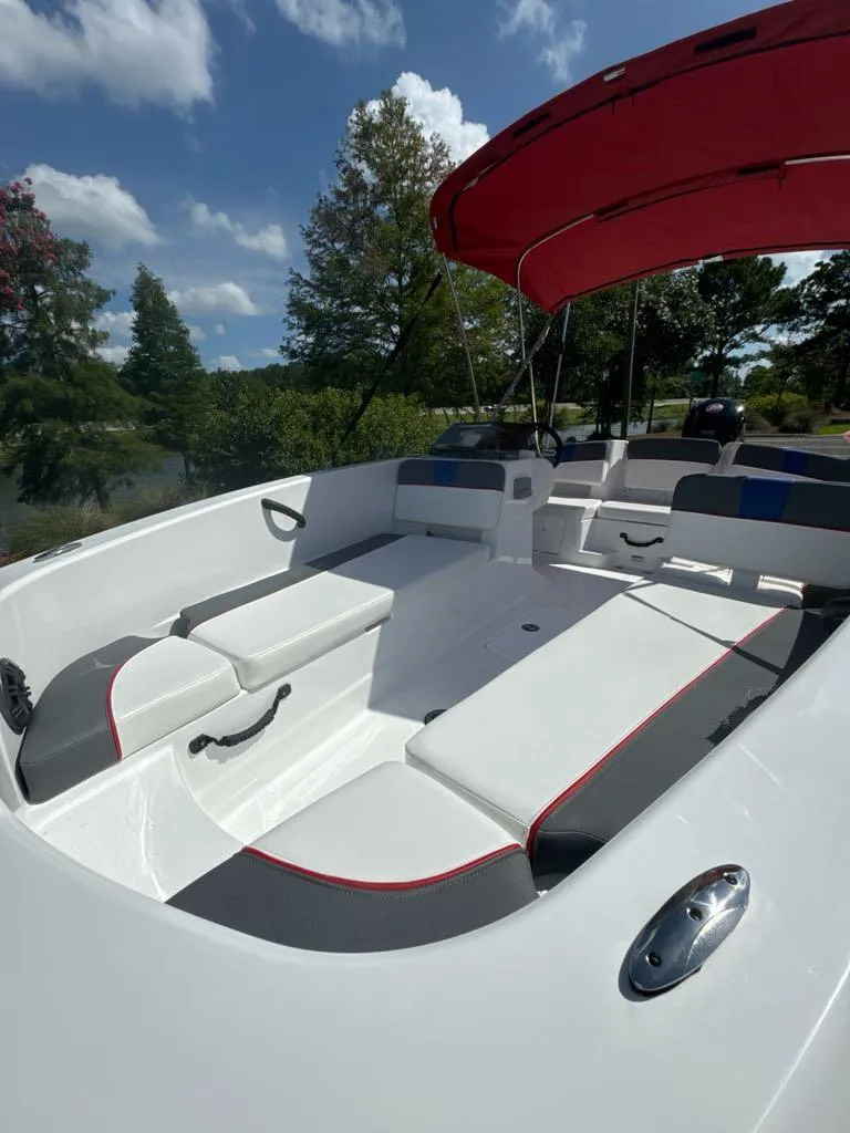 Slide: The Image of 2024 Tahoe T18 boat with red canopy and white seating, docked near a lake. - 5