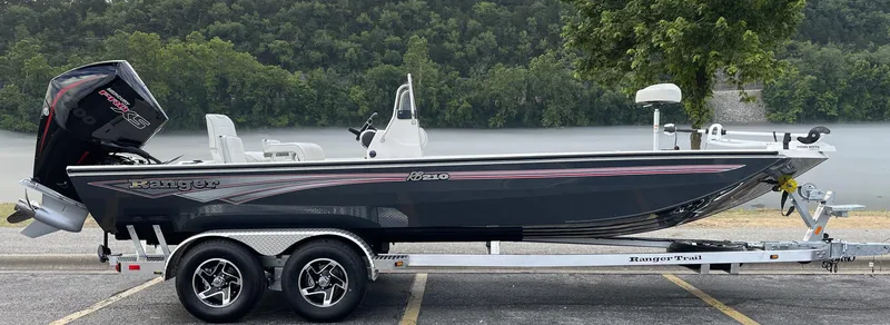 Slide: The Image of 2024 Ranger RB210 boat on trailer by a scenic riverbank. - 2