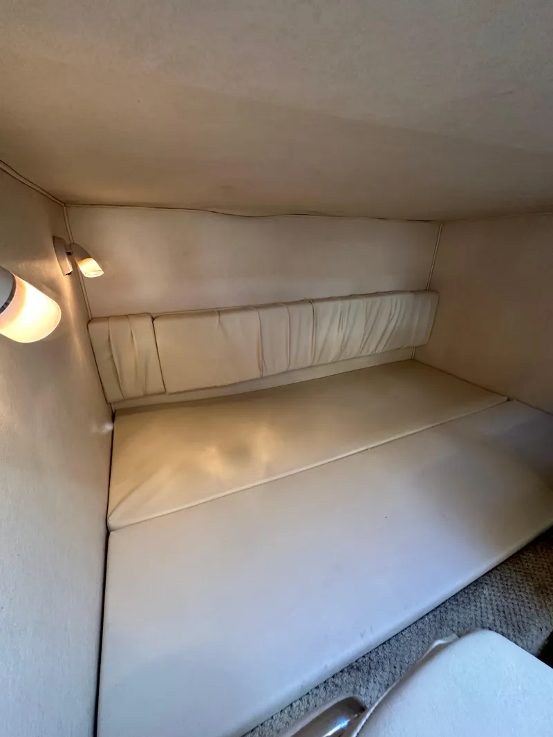 Slide: The Image of 2003 Sea Ray 290 Amberjack cabin interior with beige upholstery and soft lighting. - 16