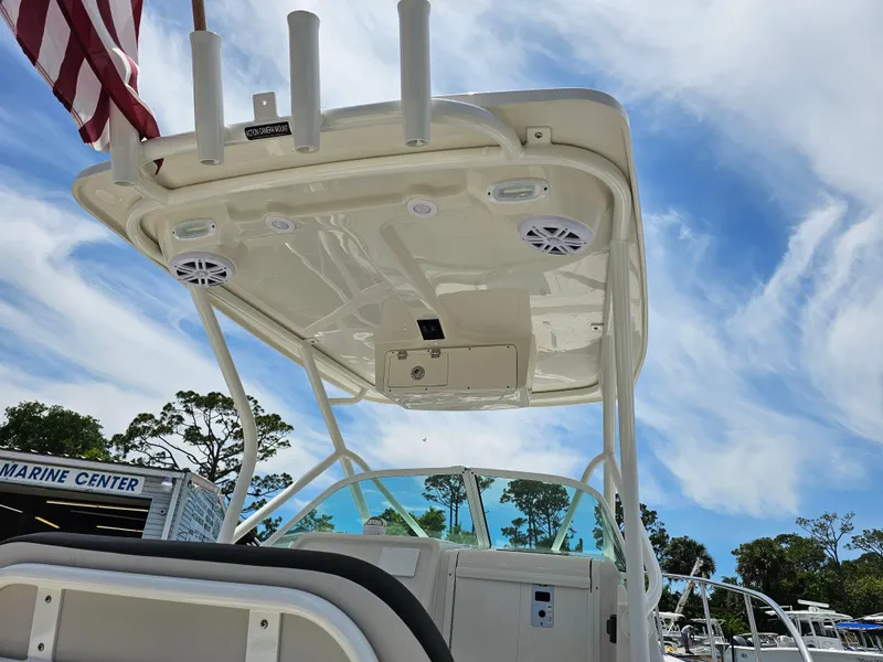 Slide: The Image of 2024 Sailfish 220 WAC boat with T-top and rod holders, docked at a marine center. - 5