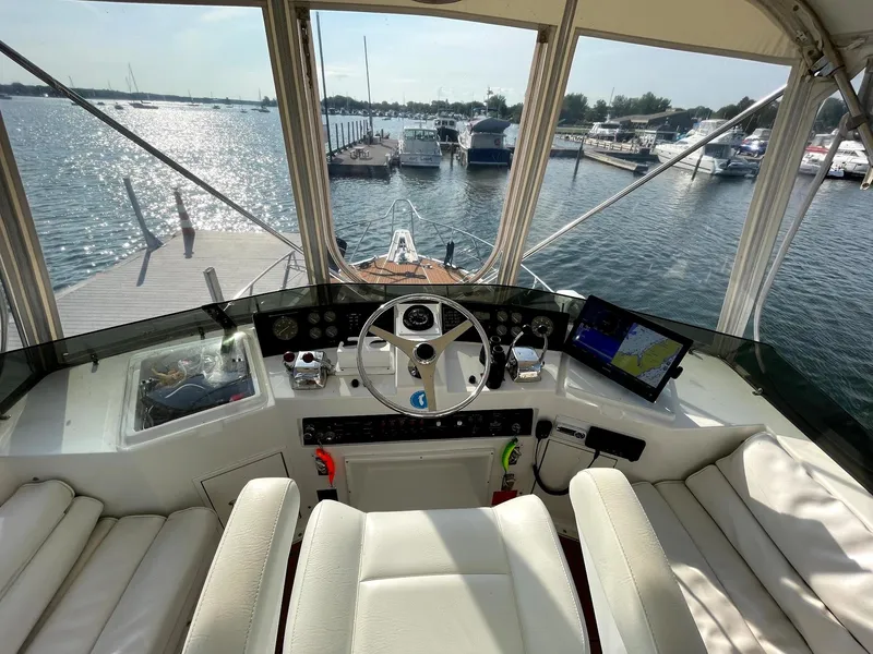Slide: The Image of 1991 Hatteras 40 Motor Yacht helm with marina view, featuring modern navigation equipment. - 10