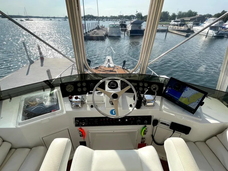 Slide: The Image of 1991 Hatteras 40 Motor Yacht helm with marina view, featuring navigation equipment and steering wheel. - 11