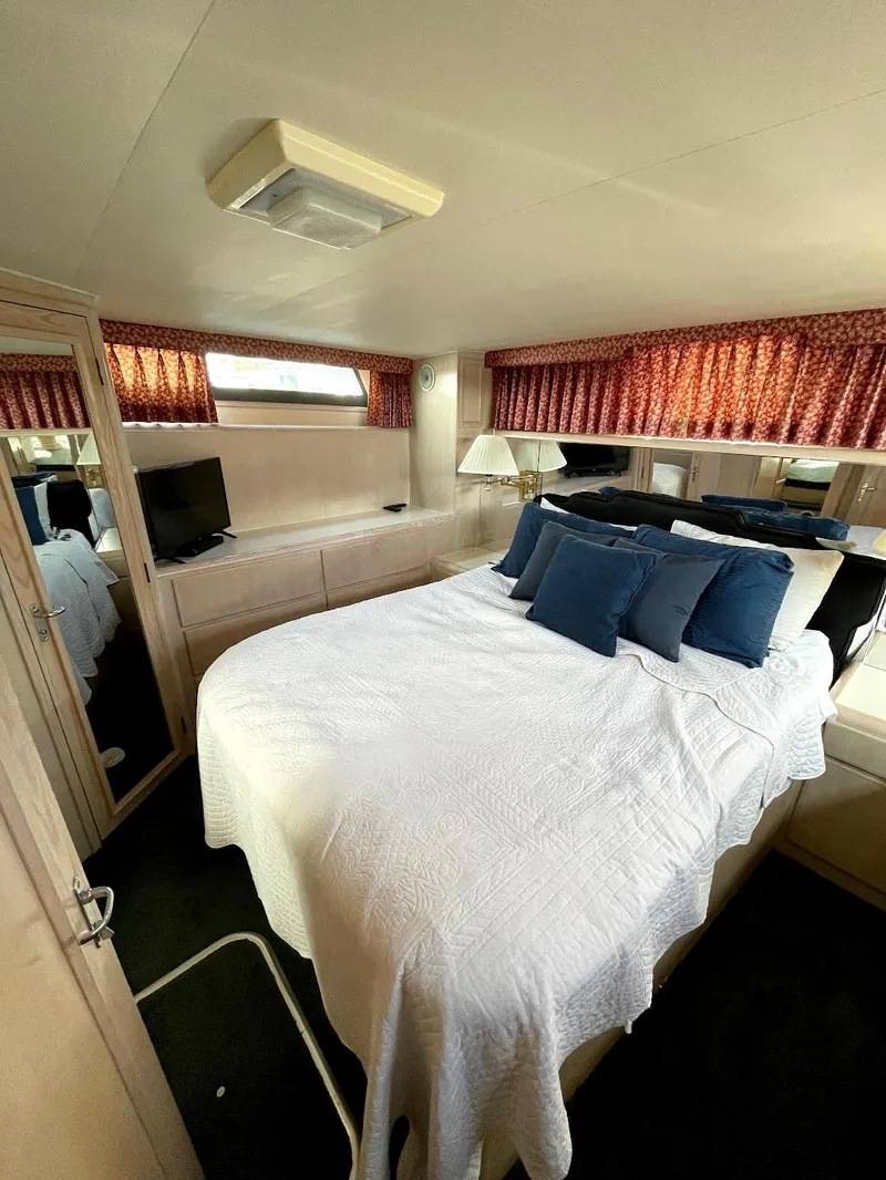 Slide: The Image of 1991 Hatteras 40 Motor Yacht bedroom with bed, TV, and red curtains. - 3