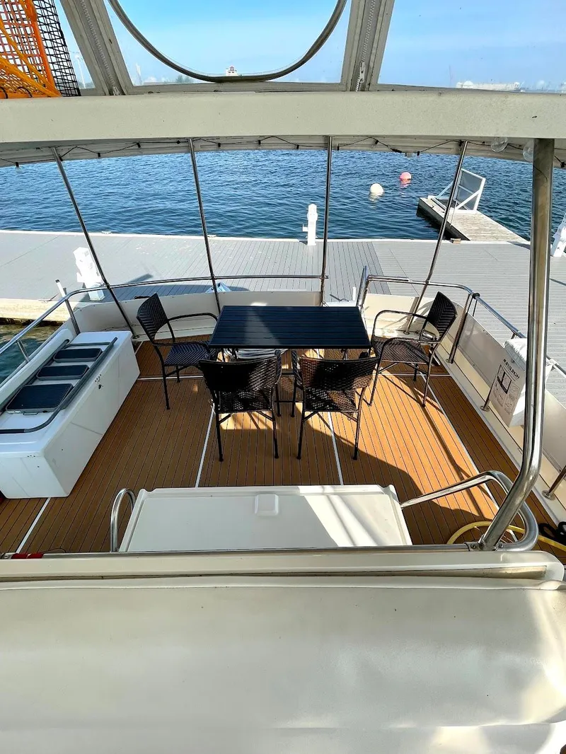 Slide: The Image of 1991 Hatteras 40 Motor Yacht deck with seating and table, docked by the water. - 6