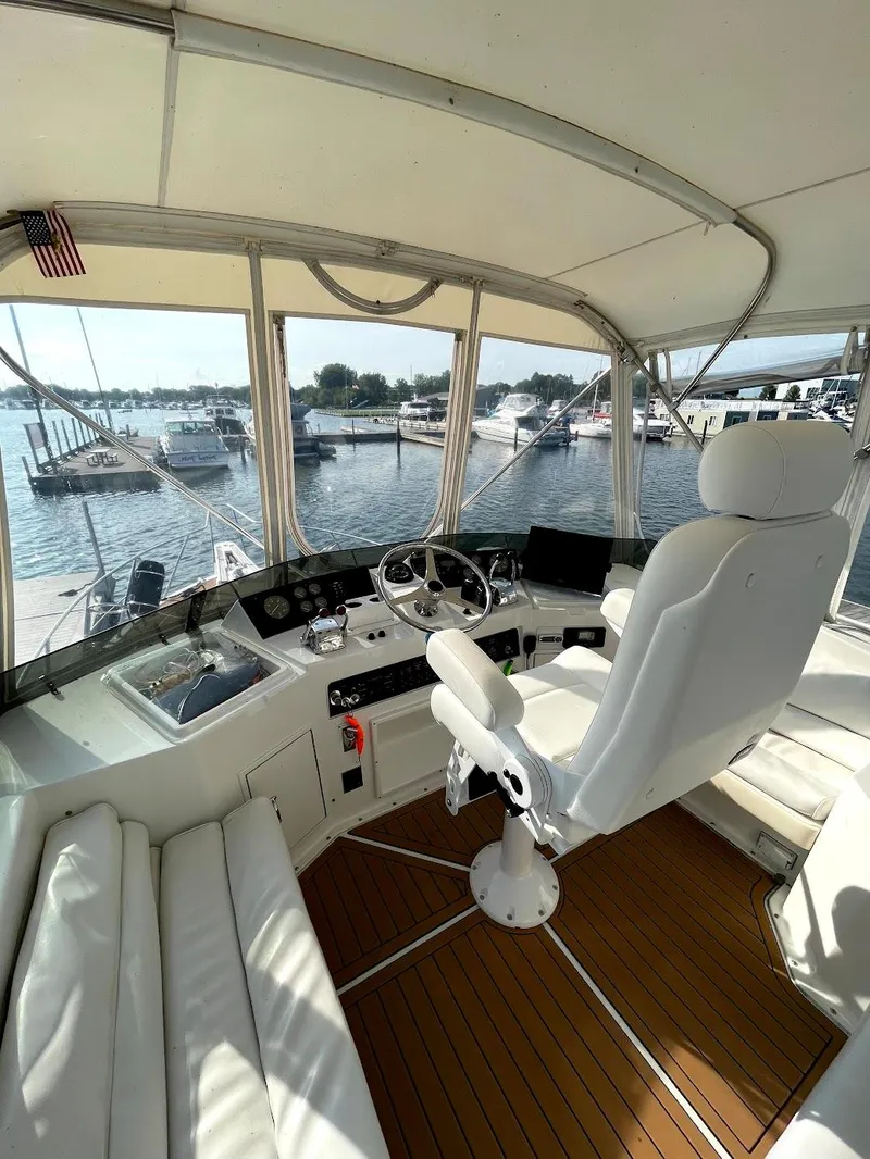 Slide: The Image of 1991 Hatteras 40 Motor Yacht helm with white seating and marina view. - 9
