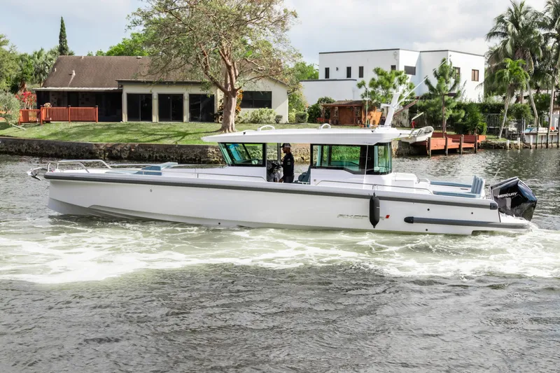 Slide: The Image of 2024 Axopar 37XC CROSS CABIN cruising on a scenic waterway near modern homes. - 22