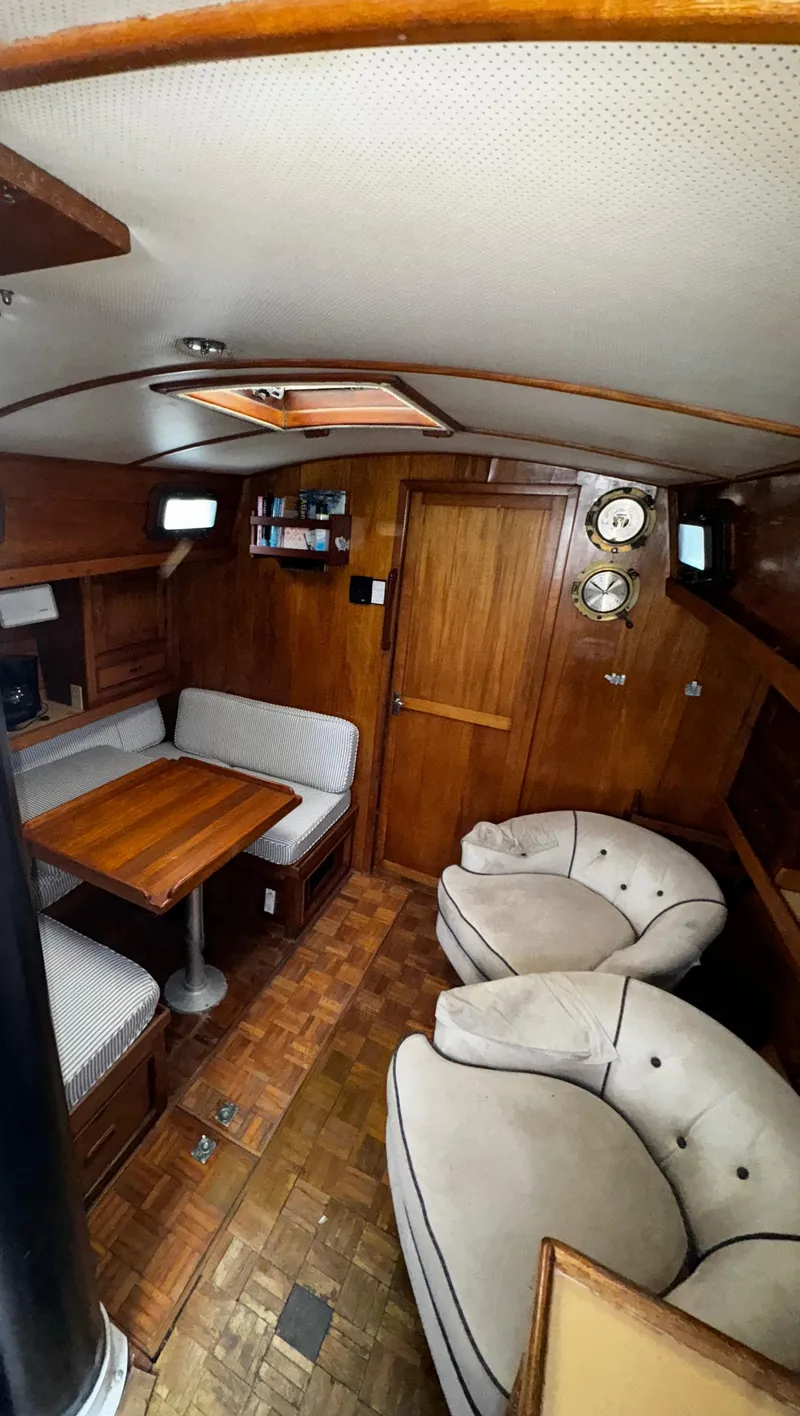 Slide: The Image of Interior of 1985 Herreshoff 38 Cat Ketch, featuring cozy seating and wooden finishes. - 13