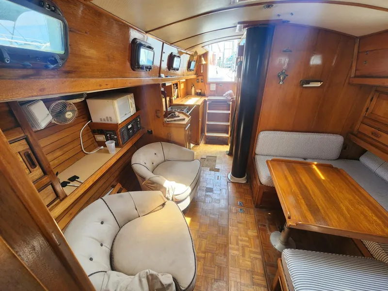 Slide: The Image of Interior of 1985 Herreshoff 38 Cat Ketch sailboat with wooden furnishings and seating area. - 14