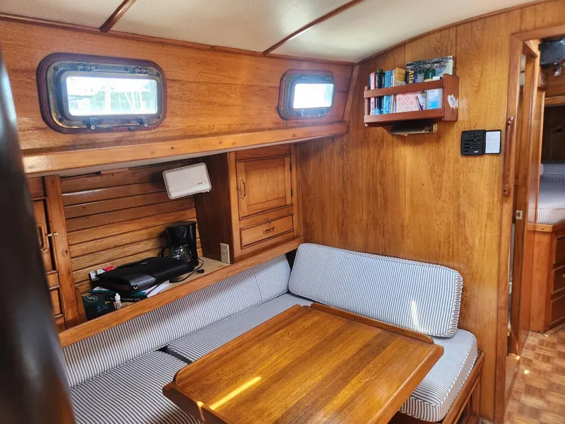Slide: The Image of Interior of 1985 Herreshoff 38 Cat Ketch sailboat with wooden furnishings and striped seating. - 15