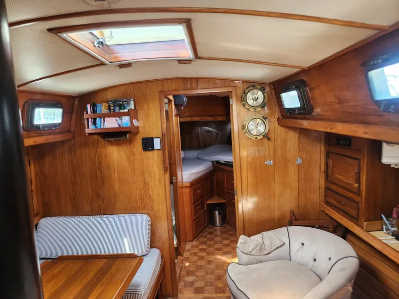 Slide: The Image of Interior of 1985 Herreshoff 38 Cat Ketch sailboat with wood paneling and cozy seating. - 16