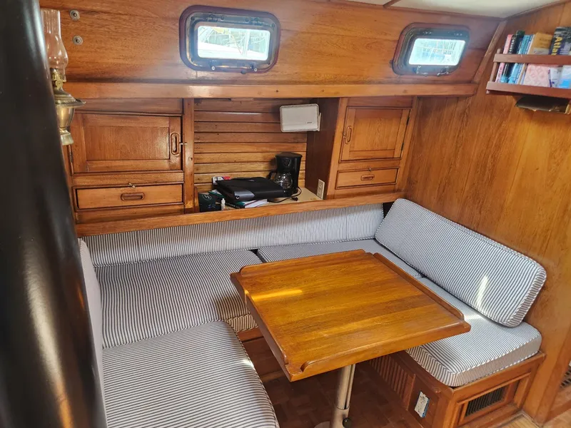 Slide: The Image of 1985 Herreshoff 38 Cat Ketch interior with wooden dining area and striped cushions. - 17
