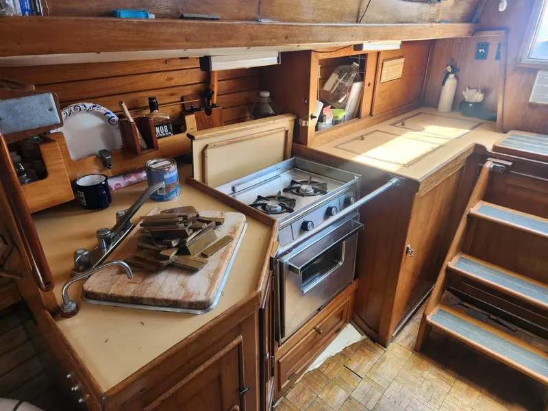 Slide: The Image of 1985 Herreshoff 38 Cat Ketch galley with stove, sink, and wooden cabinetry. - 18