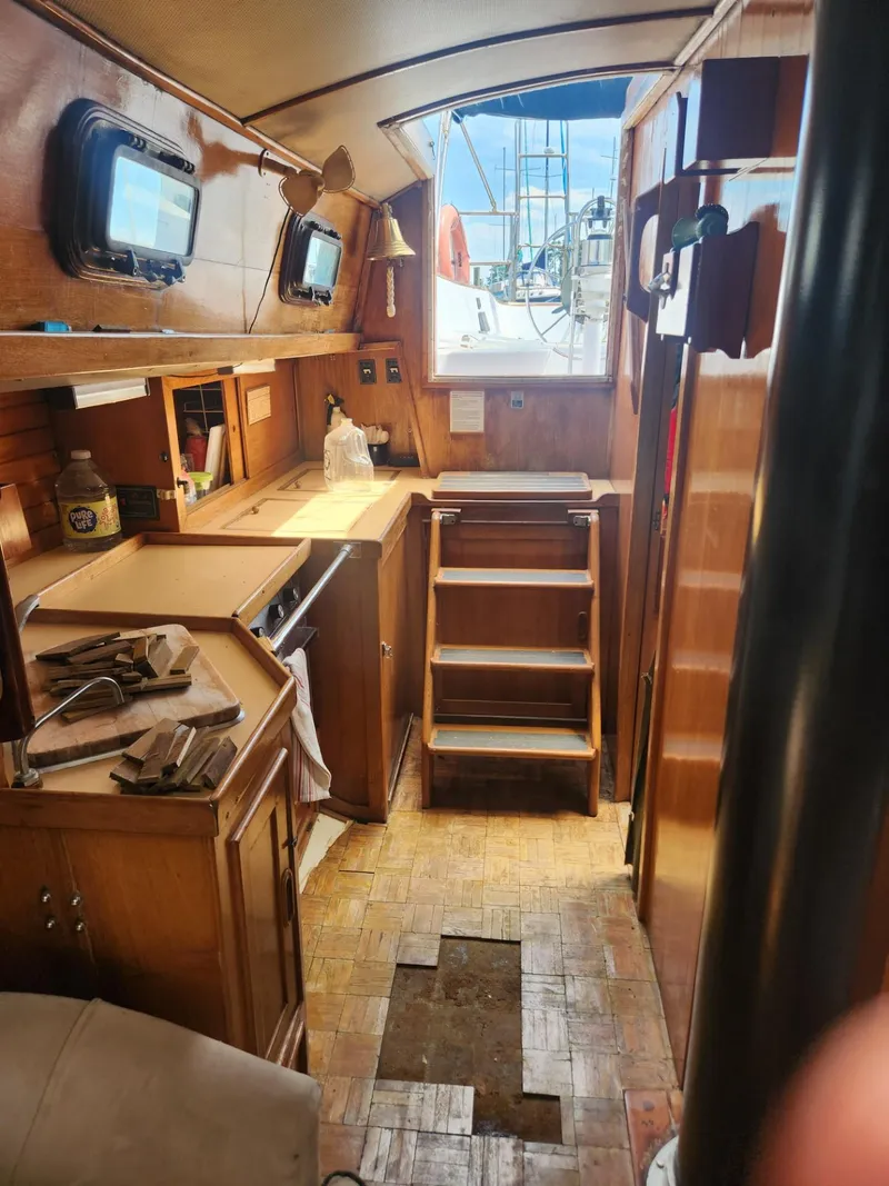 Slide: The Image of Interior of 1985 Herreshoff 38 Cat Ketch sailboat with wooden cabinetry and steps. - 21