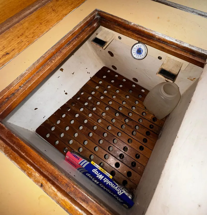 Slide: The Image of 1985 Herreshoff 38 Cat Ketch interior storage compartment with wooden slats and thermometer. - 23