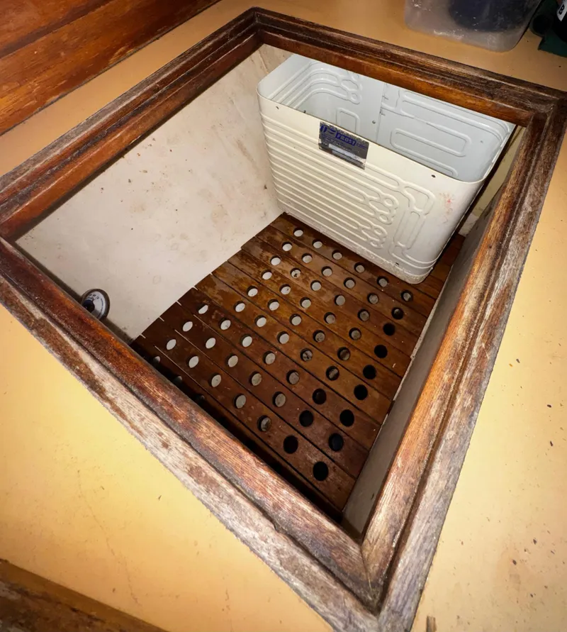Slide: The Image of 1985 Herreshoff 38 Cat Ketch interior storage compartment with wooden slats and white panel. - 24