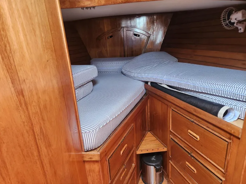 Slide: The Image of 1985 Herreshoff 38 Cat Ketch cabin with wooden interior and striped bedding. - 25