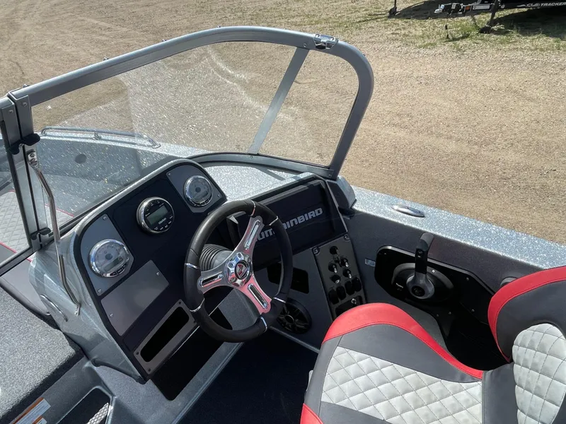 Slide: The Image of 2022 Triton 206 Allure boat dashboard and steering wheel with red and gray seating. - 7