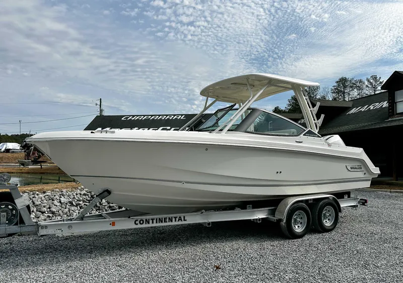 Slide: The Image of 2025 Boston Whaler 240 Vantage on trailer, in front of wooden building. - 3