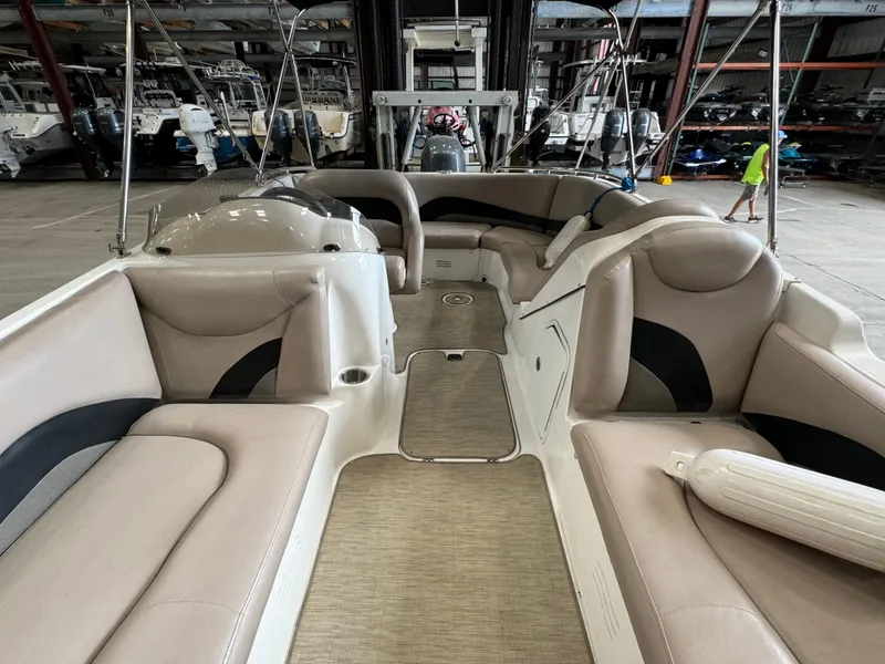 Slide: The Image of 2014 Hurricane SunDeck Sport 202 OB interior with beige seating in a storage facility. - 7