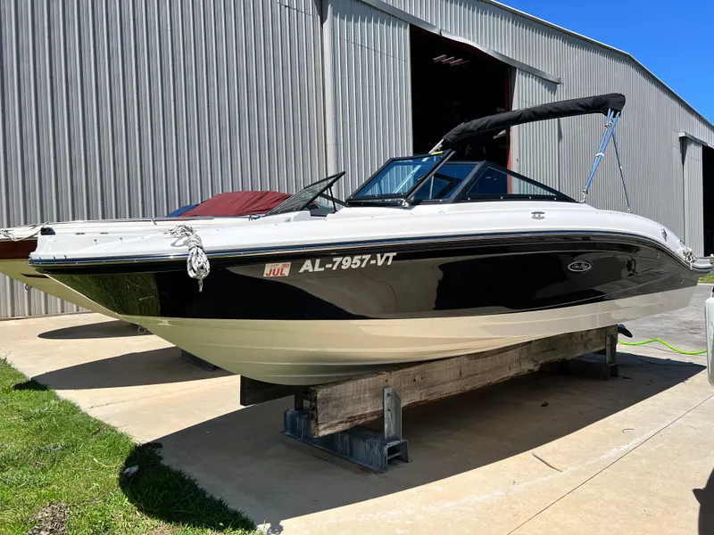 Slide: The Image of 2023 Sea Ray SPX 210 boat on a trailer outside a metal building. - 2