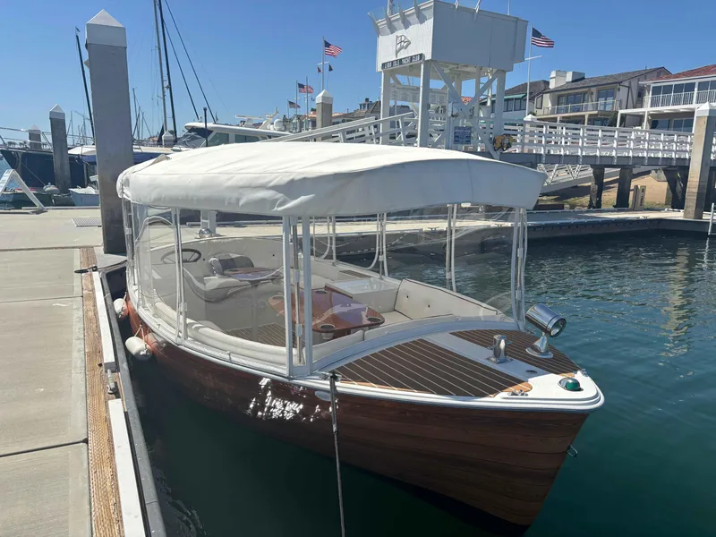Slide: The Image of 2013 Duffy Snug Harbor boat docked at marina with clear canopy and flags in background. - 4