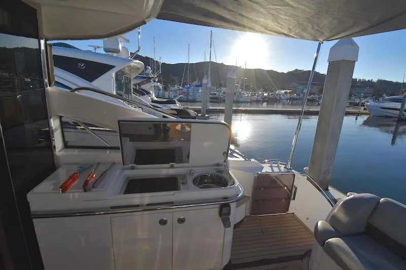 Slide: The Image of 2013 Princess V52 yacht at marina, featuring outdoor kitchen and seating area. - 19