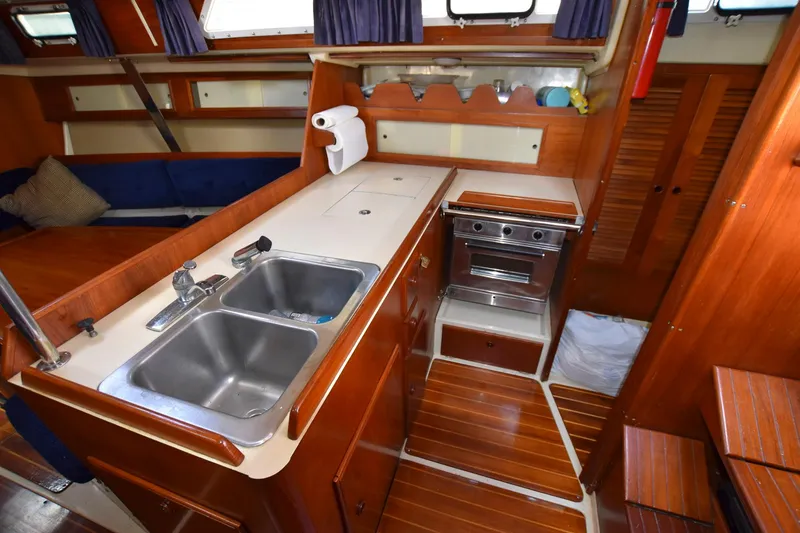 Slide: The Image of 1985 Pearson 36-2 sailboat galley with double sink, stove, and wooden cabinetry. - 21