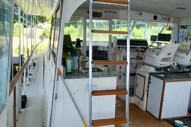 Slide: The Image of 1976 Bertram 58 Flybridge Motor Yacht interior with helm, ladder, and seating area. - 45