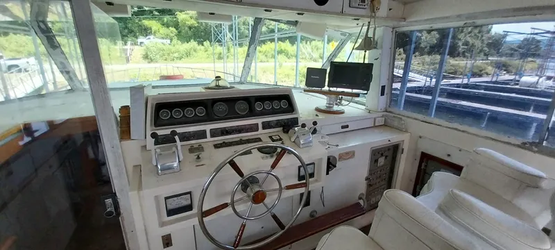 Slide: The Image of 1976 Bertram 58 Flybridge Motor Yacht helm with classic controls and panoramic windows. - 48