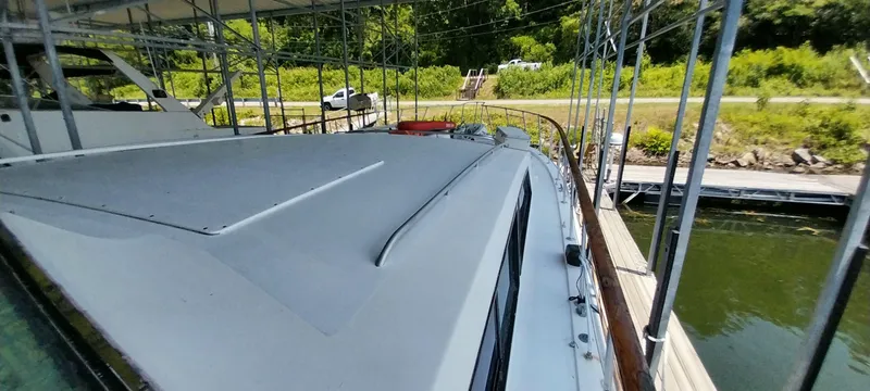 Slide: The Image of 1976 Bertram 58 Flybridge Motor Yacht docked under a canopy. - 54