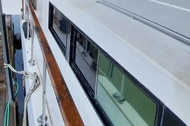 Slide: The Image of 1976 Bertram 58 Flybridge Motor Yacht side view with windows and docked at marina. - 55