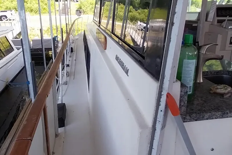 Slide: The Image of 1976 Bertram 58 Flybridge Motor Yacht side deck with railing and cabin windows. - 57