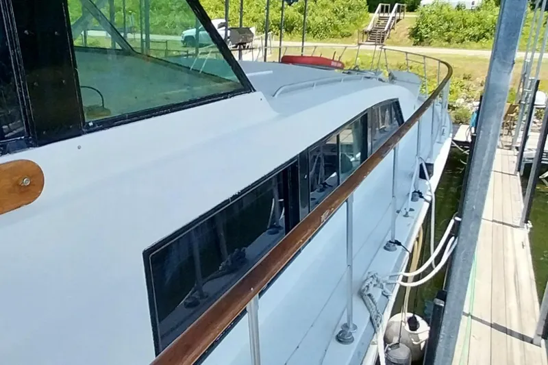 Slide: The Image of 1976 Bertram 58 Flybridge Motor Yacht docked, showcasing sleek design and spacious deck. - 58