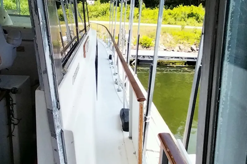 Slide: The Image of 1976 Bertram 58 Flybridge Motor Yacht deck view with railing and water in background. - 67