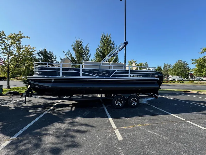 Slide: The Image of 2024 Ranger Reata 223F pontoon boat on trailer in parking lot. - 0