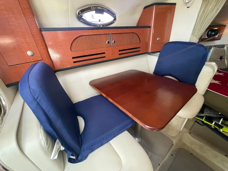 Slide: The Image of Interior of 2006 Sea Ray 280 Sundancer with wooden table and blue cushioned seats. - 28