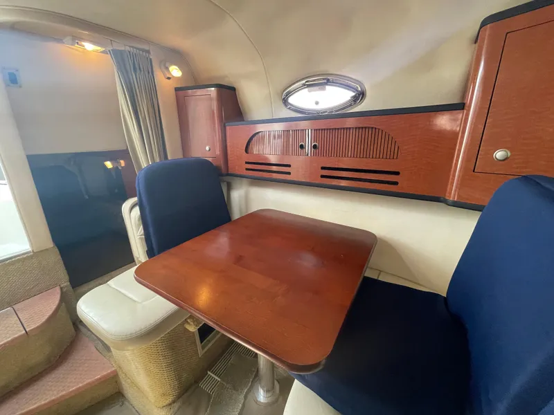Slide: The Image of Interior of 2006 Sea Ray 280 Sundancer with wooden table and blue seating. - 32