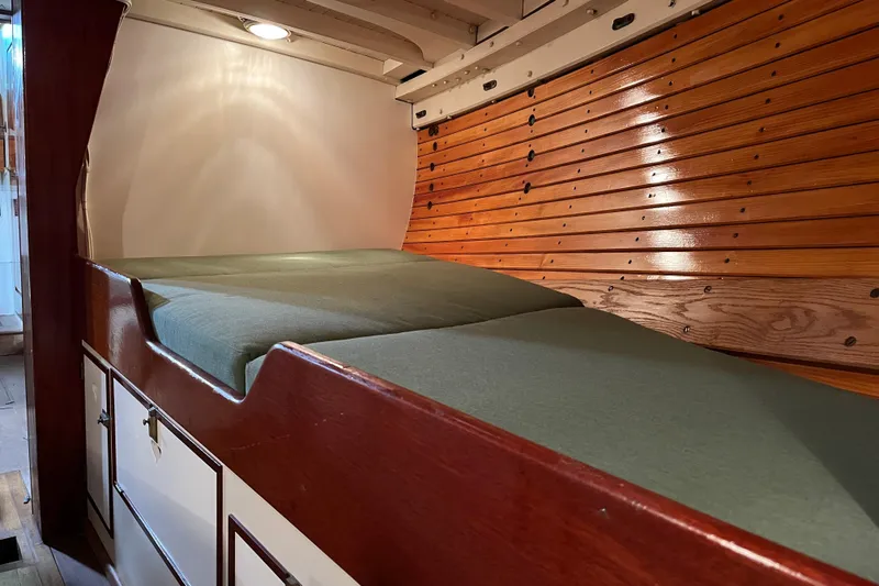 Slide: The Image of Interior of a 1999 Custom Lyle Hess Cutter with wooden paneling and a cozy sleeping area. - 16