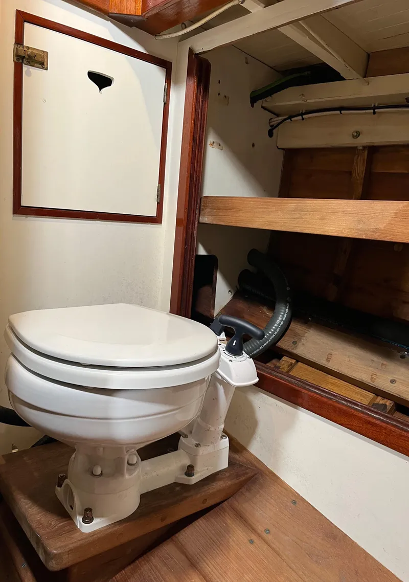 Slide: The Image of 1999 Custom Lyle Hess Cutter boat interior with marine toilet and wooden storage shelves. - 24