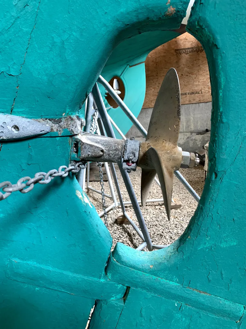 Slide: The Image of Propeller of 1999 Custom Lyle Hess Cutter sailboat, viewed through turquoise hull opening. - 28