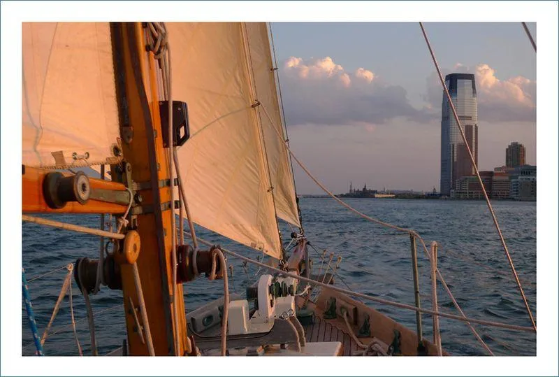 Slide: The Image of Sailing on a 1999 Custom Lyle Hess Cutter near a city skyline at sunset. - 6