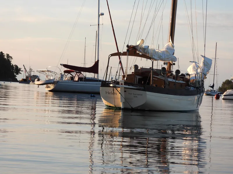 Slide: The Image of Sailboats anchored on calm water at sunset, featuring a 1999 Custom Lyle Hess Cutter. - 8