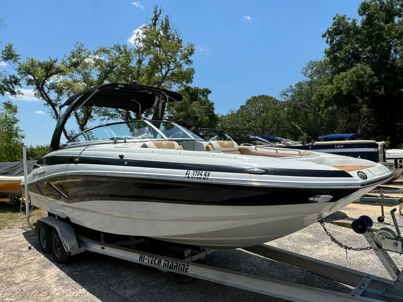 Slide: The Image of 2021 Crownline E275 XS boat on trailer, parked outdoors under clear sky. - 0