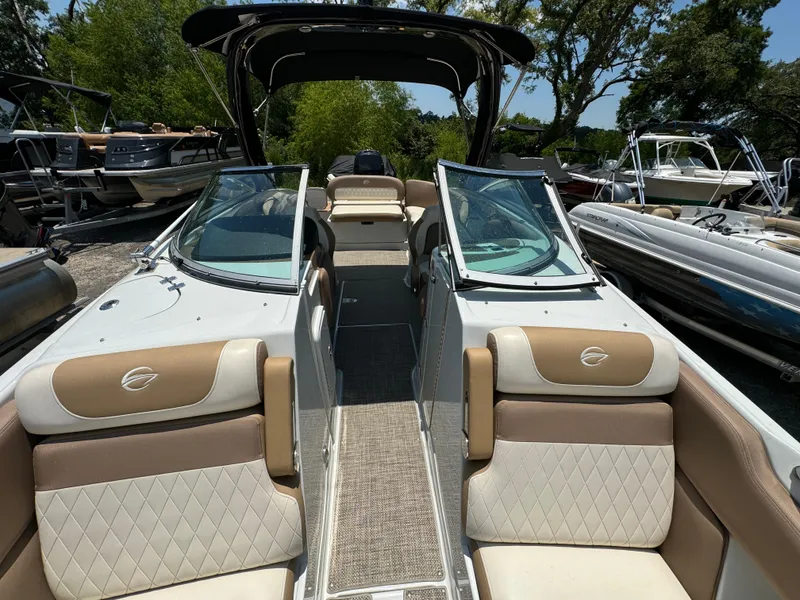 Slide: The Image of 2021 Crownline E275 XS boat interior with tan and white seating, docked among other boats. - 4