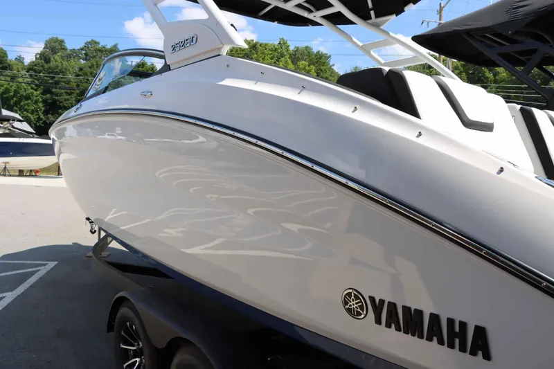 Slide: The Image of 2024 Yamaha Boats 252SD, sleek white exterior, on trailer, sunny day. - 3