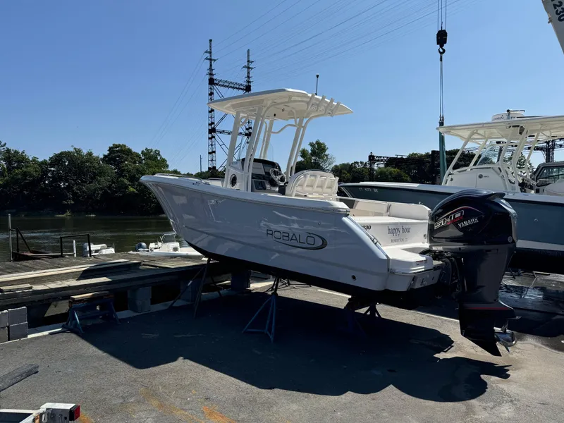 Slide: The Image of 2023 Robalo R230 Center Console boat docked near a river. - 13