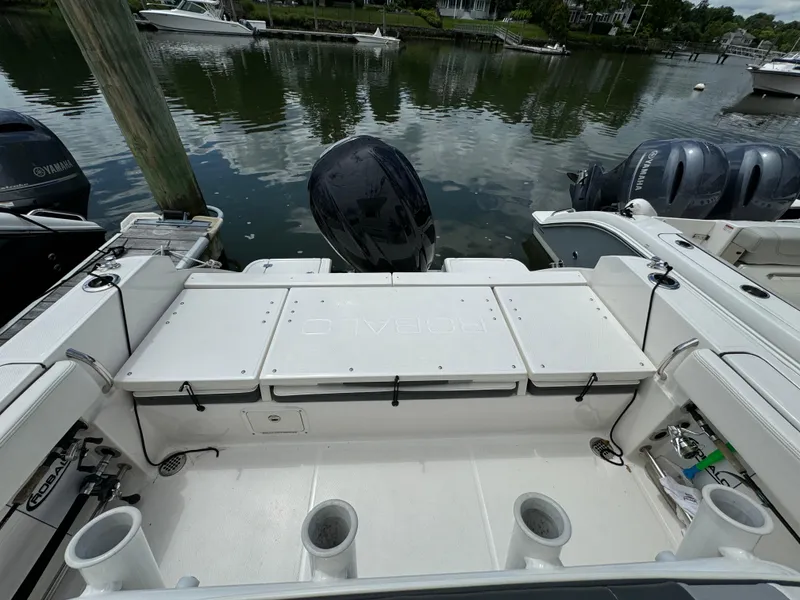Slide: The Image of 2023 Robalo R230 Center Console boat docked, showcasing the spacious rear deck and outboard motor. - 5
