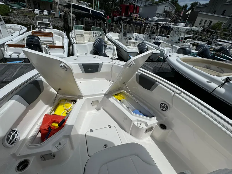 Slide: The Image of 2023 Robalo R230 Center Console boat with open storage compartments at a marina. - 9